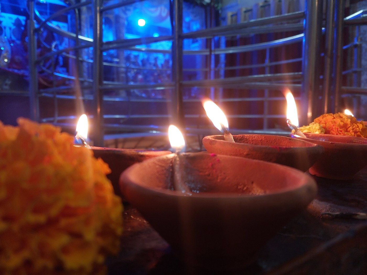 Lit clay diyas glowing with marigold petals beside them